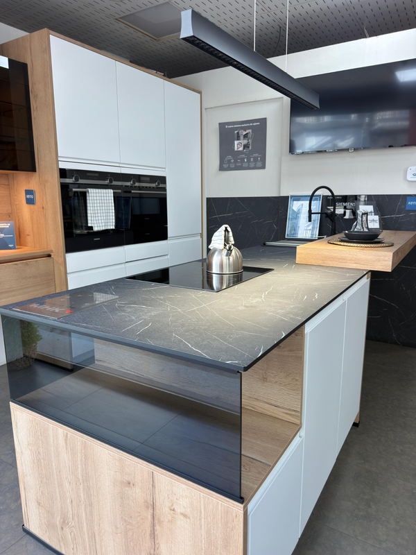 Fotografía real de nuestra cocina con isla: encimera oscura, frentes blancos y detalles de acabado madera
